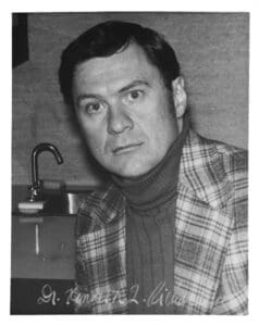 A man in plaid jacket and sweater standing next to sink.