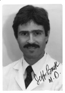 A black and white photo of a man with a mustache.