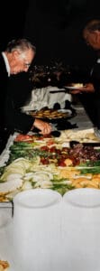 A person holding a plate of food on top of a table.