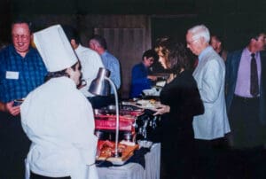 A group of people standing around a buffet table.
