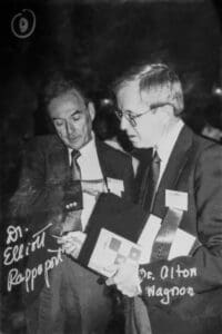Two men are looking at a book together.