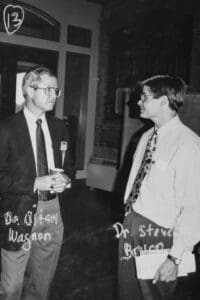 Two men standing next to each other talking.