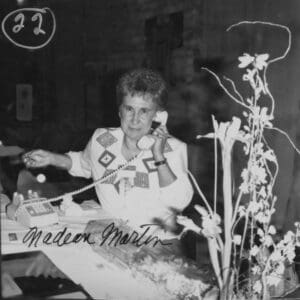 A woman sitting in front of some flowers.
