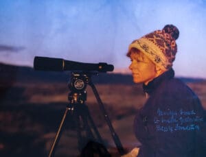 A woman looking through the telescope at dusk.
